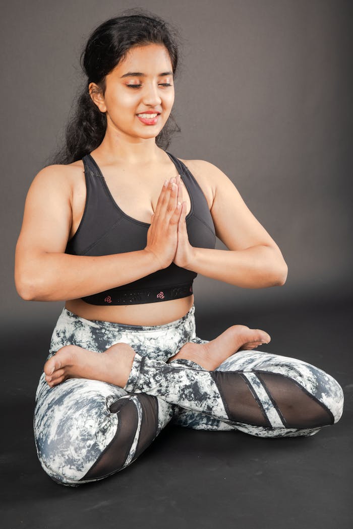 South Asian woman in yoga pose indoors, promoting mindfulness and flexibility.