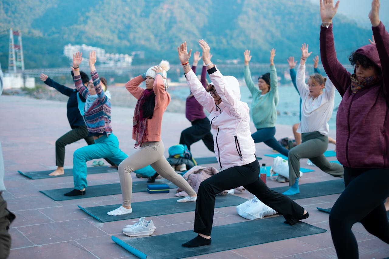 A diverse group of people practicing yoga together outdoors with stunning mountain views.